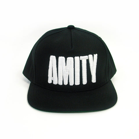 image of the front of a black snapback hat. front has large white embroidery that says amity