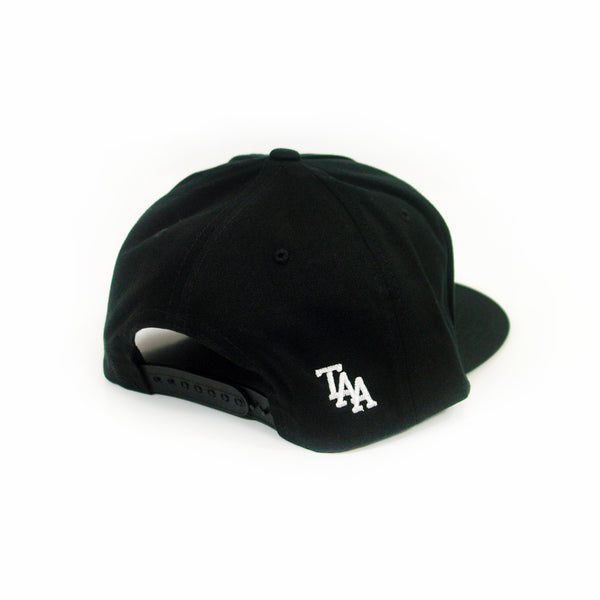 image of the back of a black snapback hat. small white embroidery on the bottom right of the letters T A A