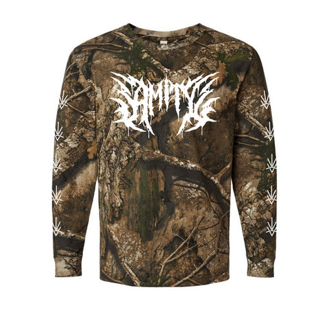 A long-sleeve camouflage shirt from The Amity Affliction, featuring white jagged text across the chest and leaf symbols on the sleeves. The brown, green, and tan tree-leaf print creates a bold outdoor look.